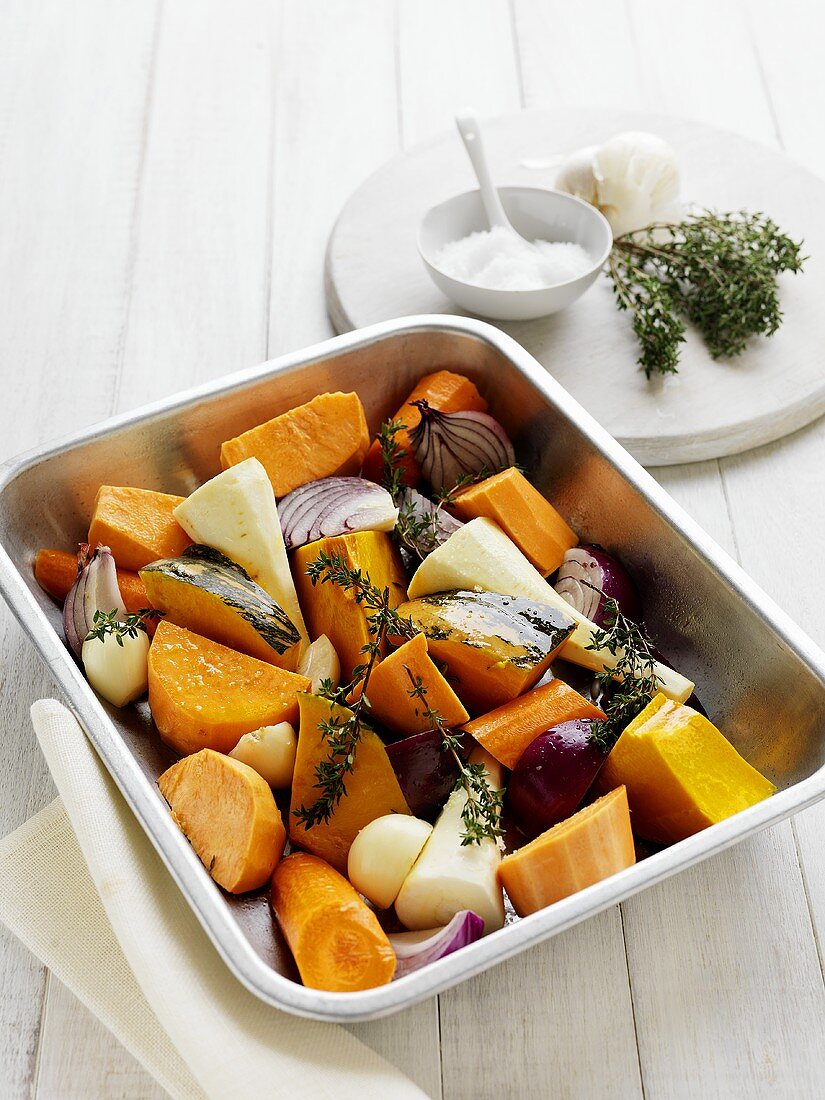 Root vegetables, onions and thyme in roasting dish