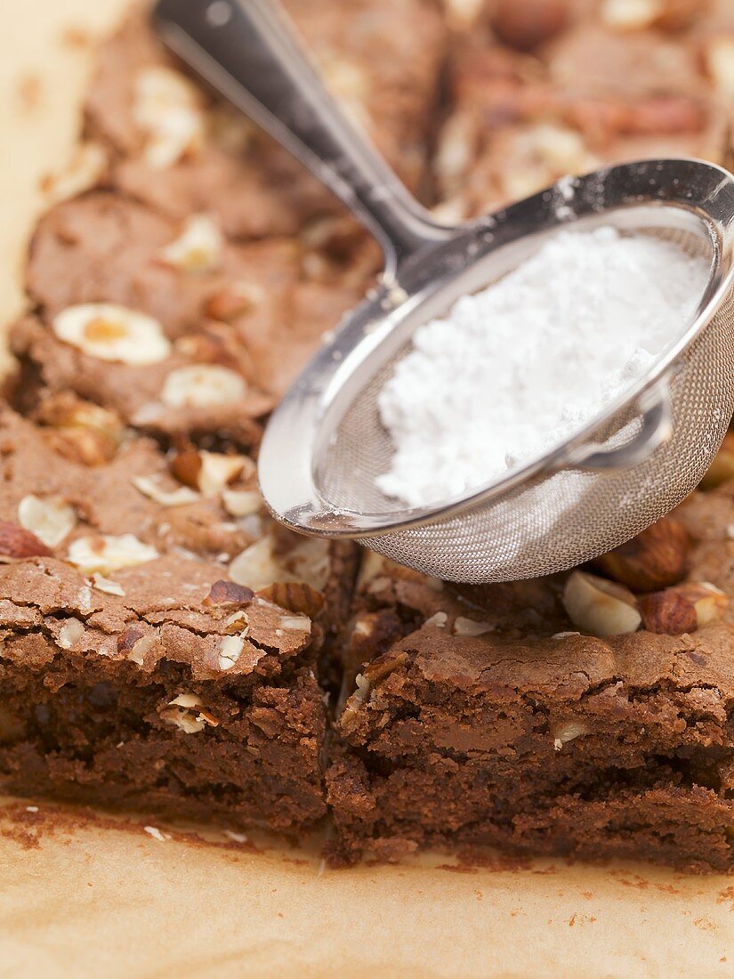 Nut brownies and sieve with icing sugar