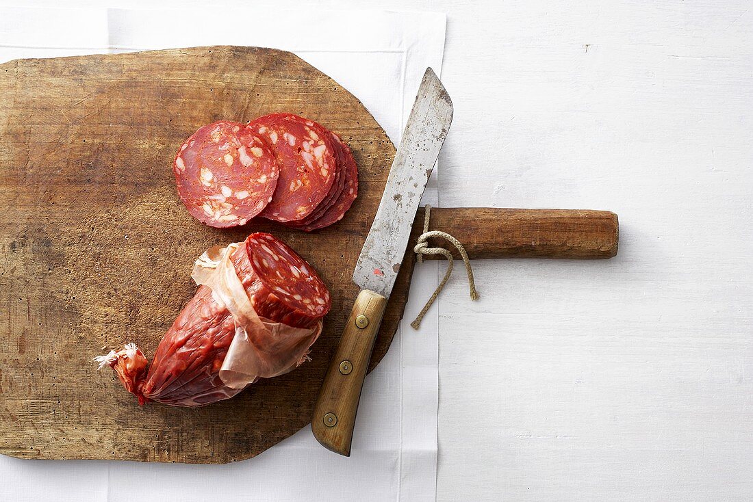 Chorizo with knife on wooden board