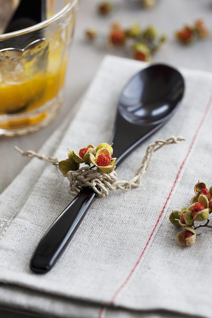 A wooden spoon decorated with berries on a linen cloth