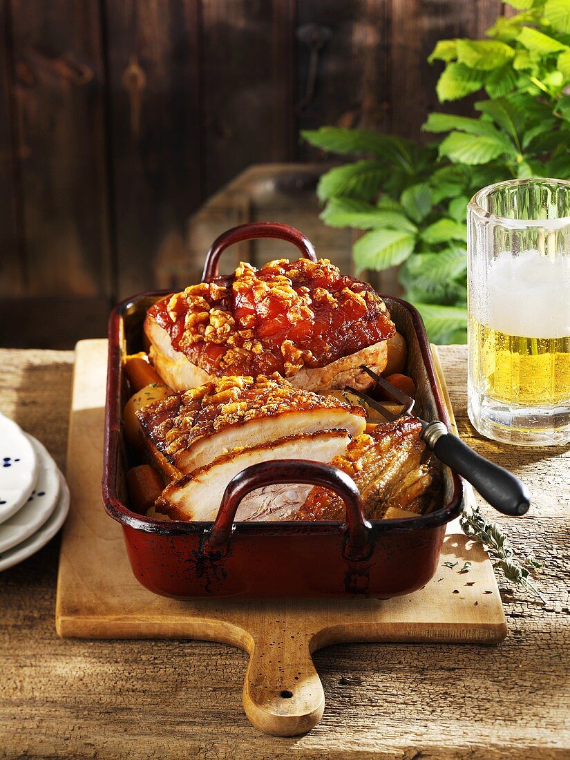 Roast pork with crackling in roasting dish, beer