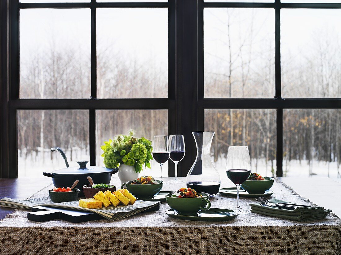 A table laid with chili con carne, corn bread and red wine