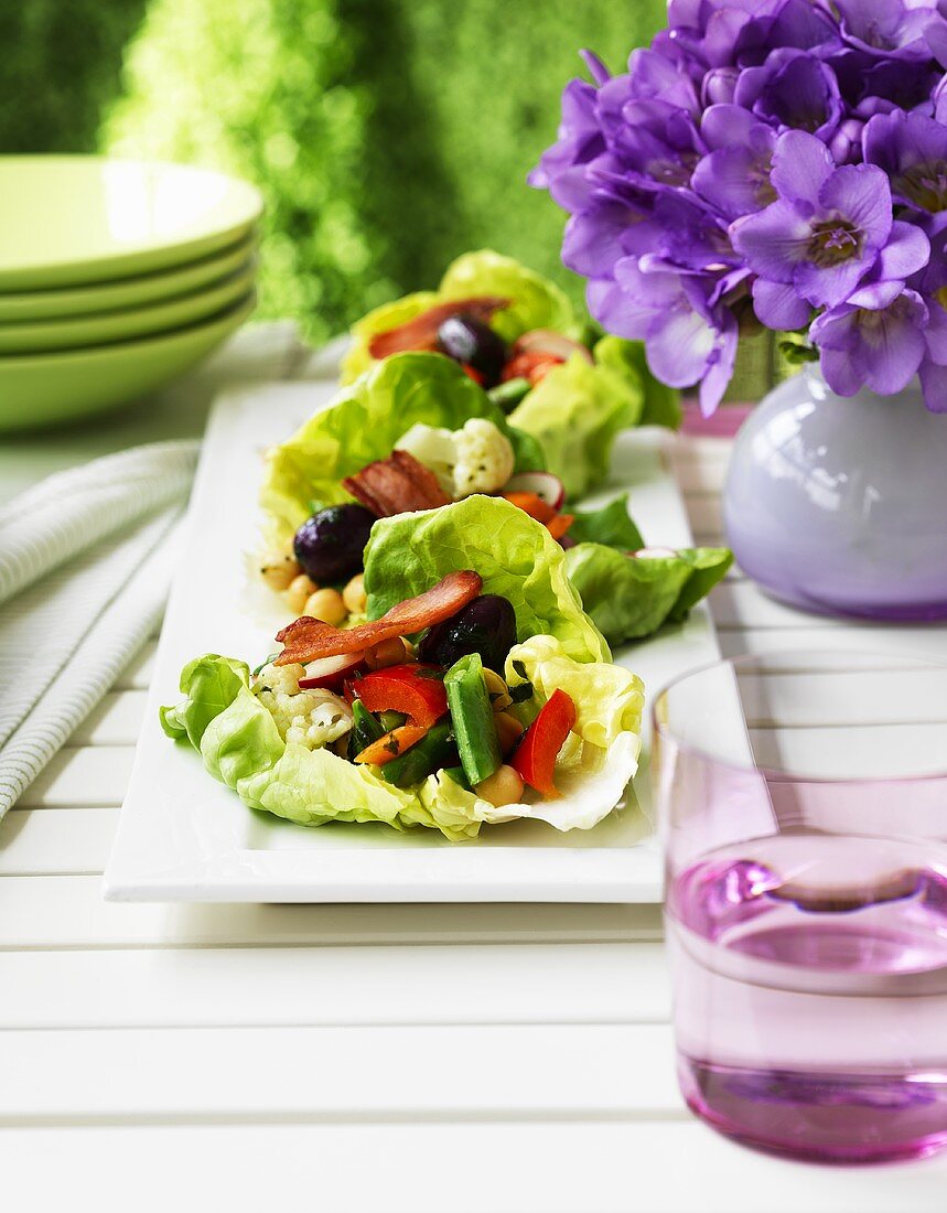 Vegetable salad with pancetta on lettuce leaves