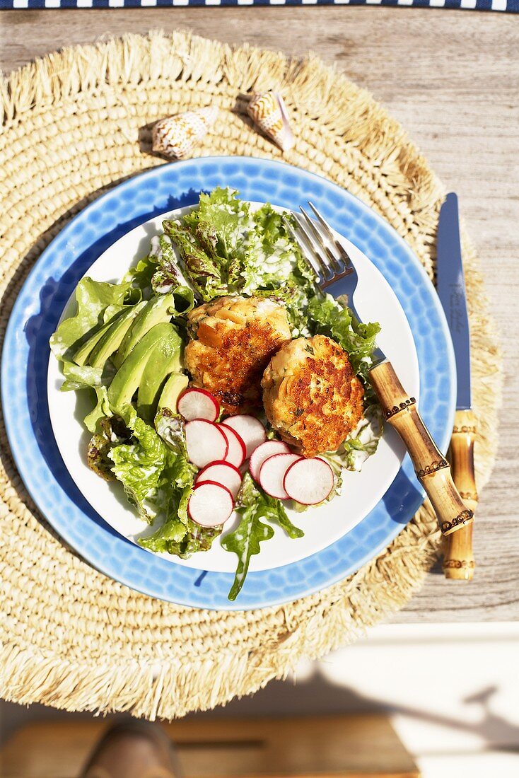 Salmon cakes with radishes, avocado and green salad