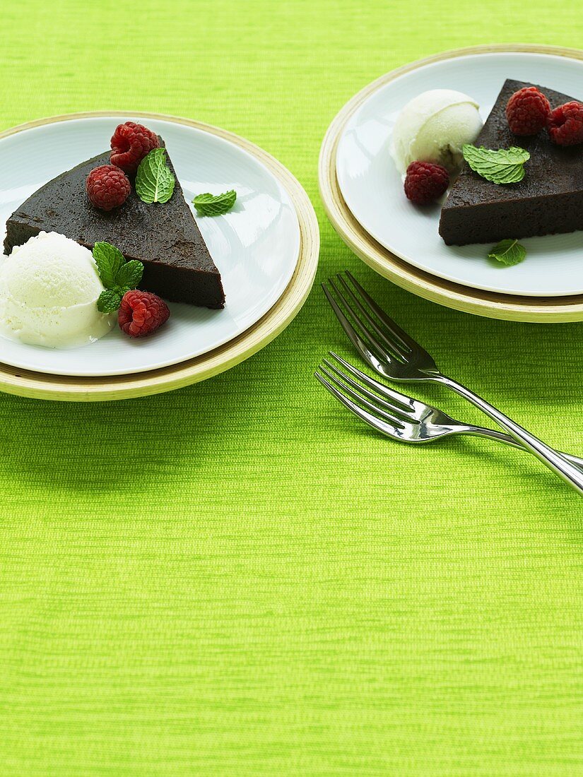 Slices of chocolate tart with vanilla ice cream and raspberries