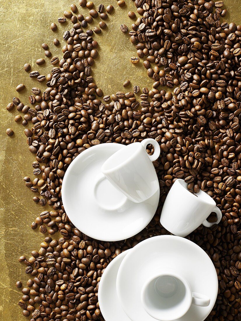 White espresso cups and saucers on coffee beans