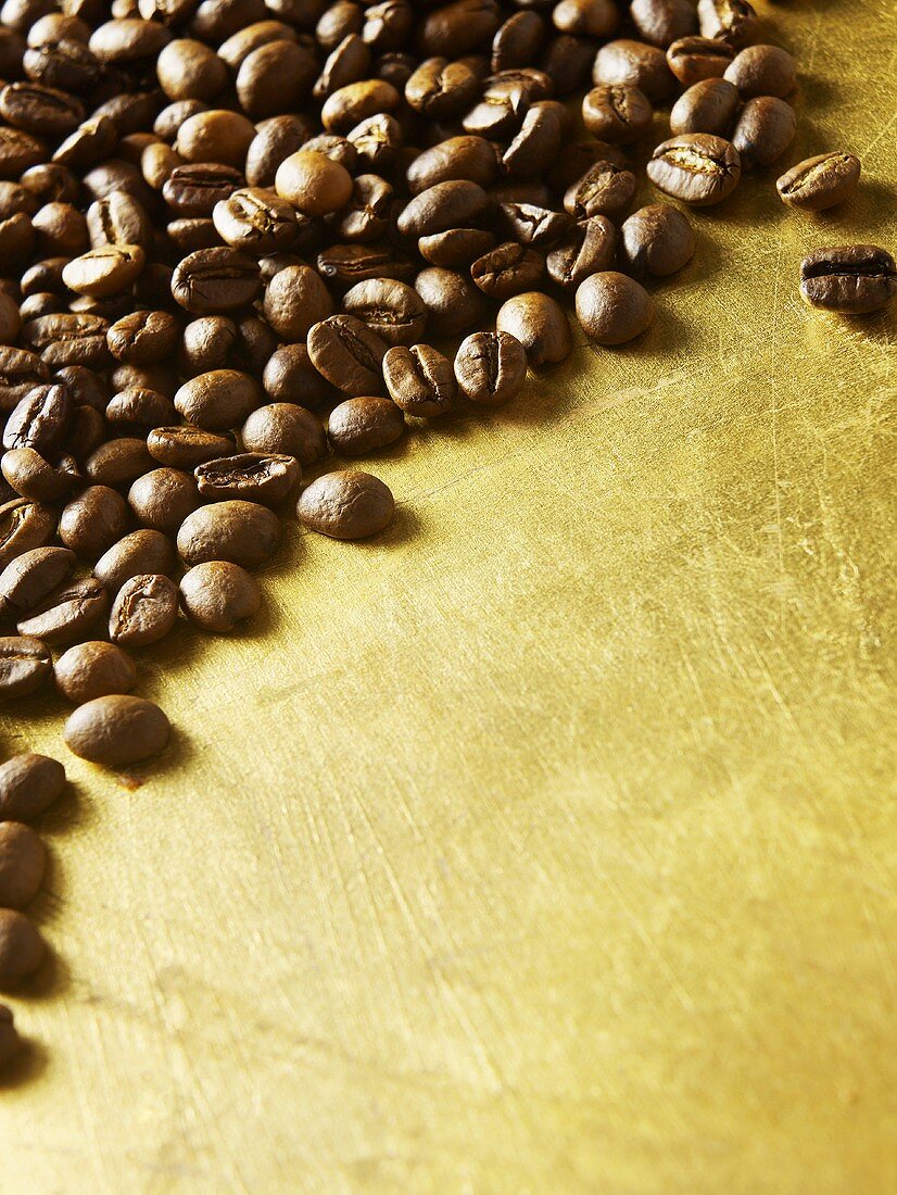 Kaffeebohnen auf goldenem Untergrund