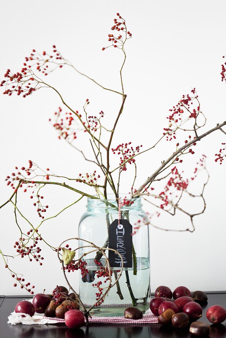 Herbstdeko mit Zweigen, Zieräpfeln und Kastanien