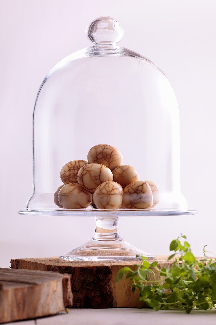 Eggs boiled in tea on cake stand with glass dome