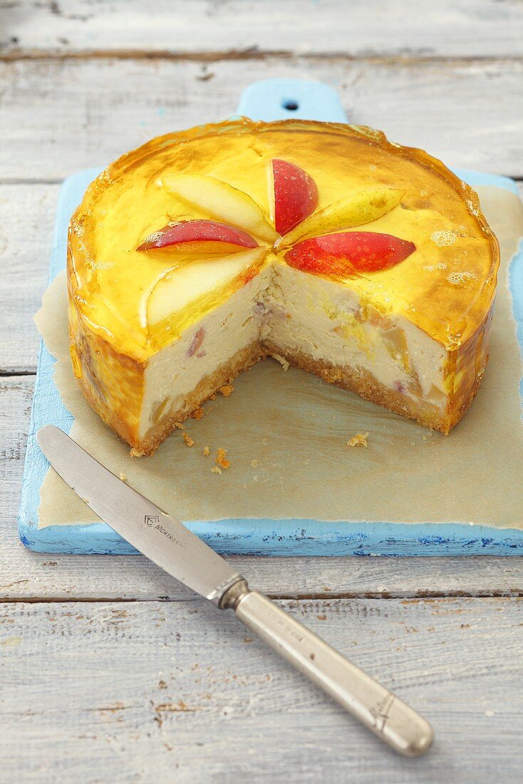 Cheesecake topped with pears, peaches and jelly, pieces removed