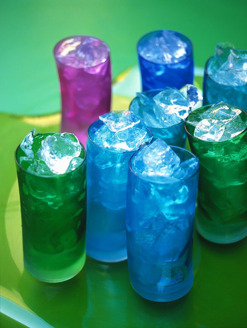 Mehrere Getränke in bunten Gläsern mit Eiswürfeln