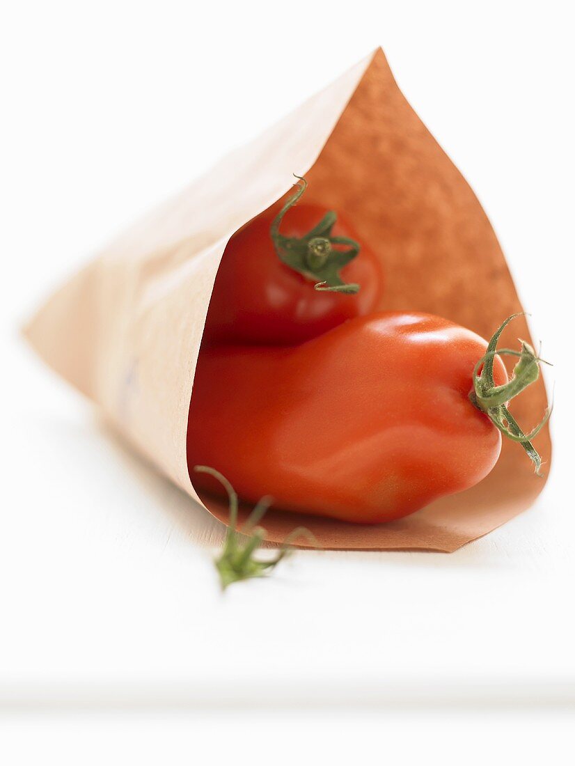 Two plum tomatoes in paper bag