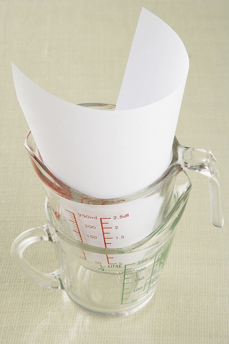 Two measuring jugs with paper