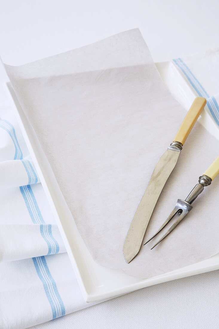 Baking tray with baking paper and a carving knife and fork