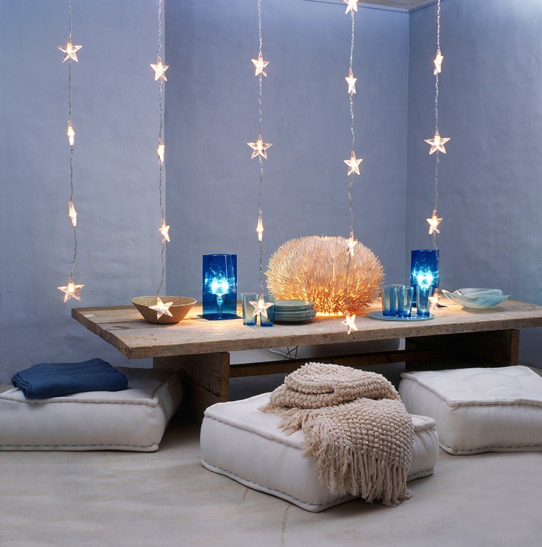 Rustic coffee table decorated with light art surrounded by floor cushions