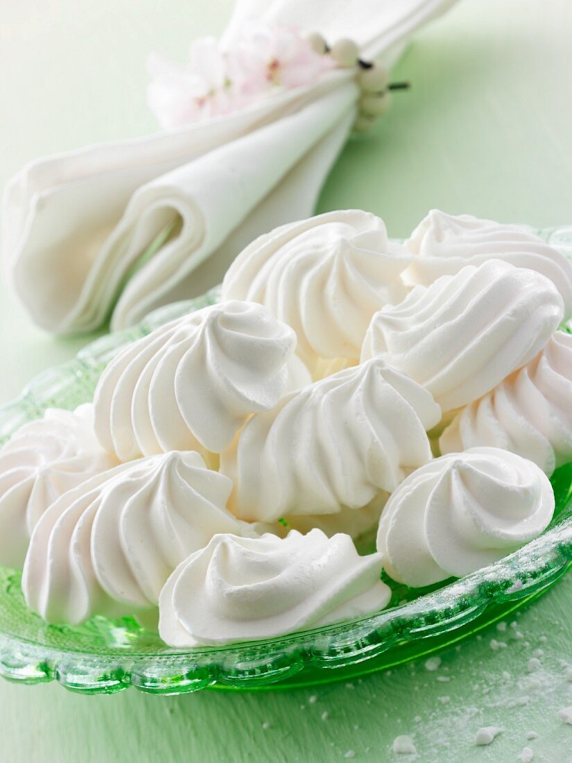 Meringues on a green plate with a napkin in the background