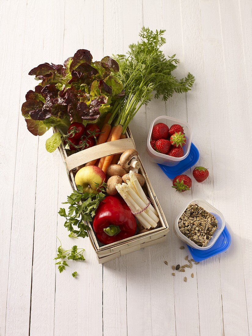 Fresh vegetables in a wooden basket, strawberries and seeds