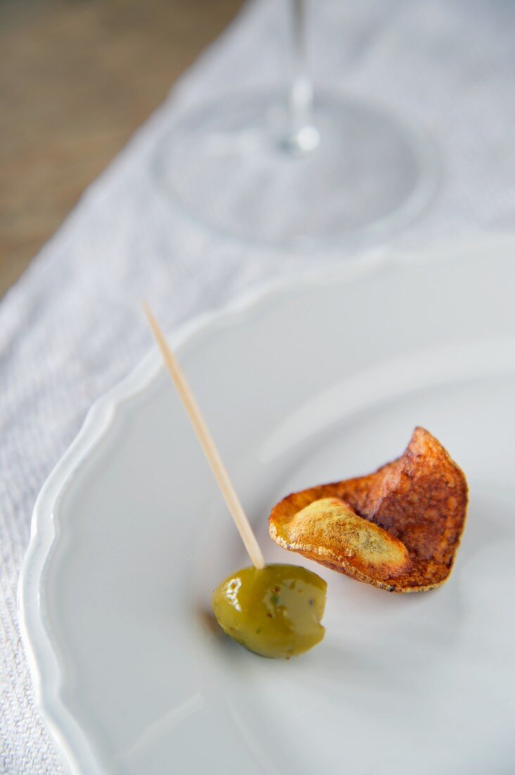 Selbstgemachter Kartoffelchip mit einer Olive