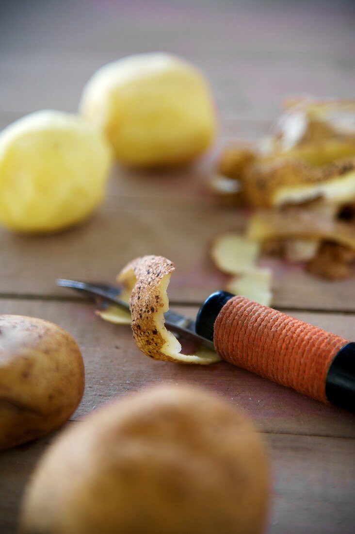 Geschälte und ungeschälte Kartoffeln, Kartoffelschale und Messer