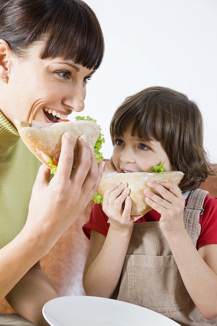 A mother and her little daughter eating sandwiches