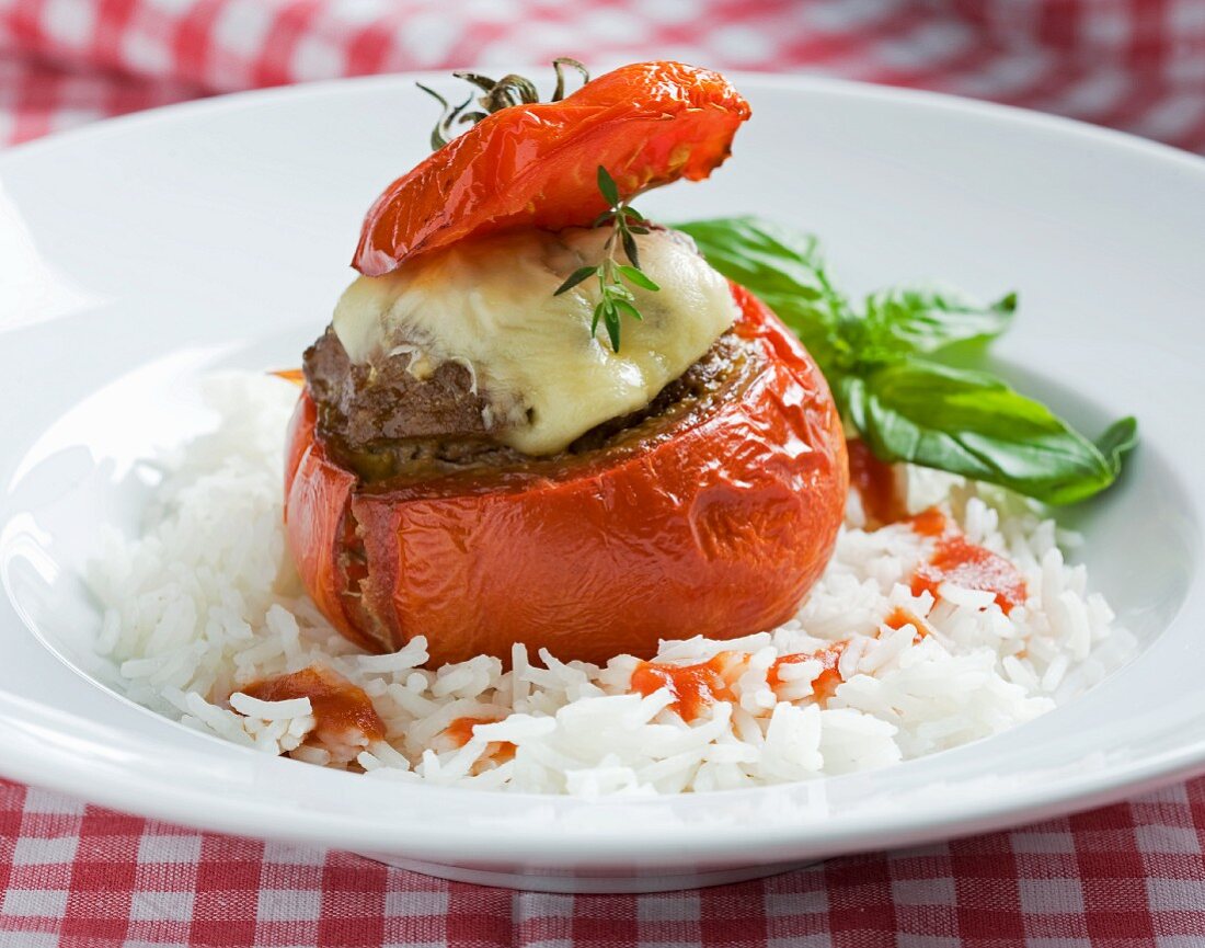 A tomato stuffed with mincemeat and cheese on a bed rice