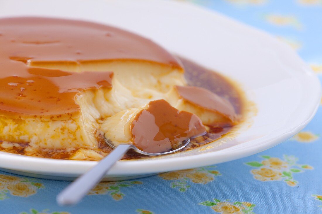 A plate of creme caramel with a spoon (close-up)