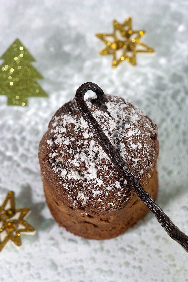 A Christmas chocolate cake with icing sugar and a vanilla pod