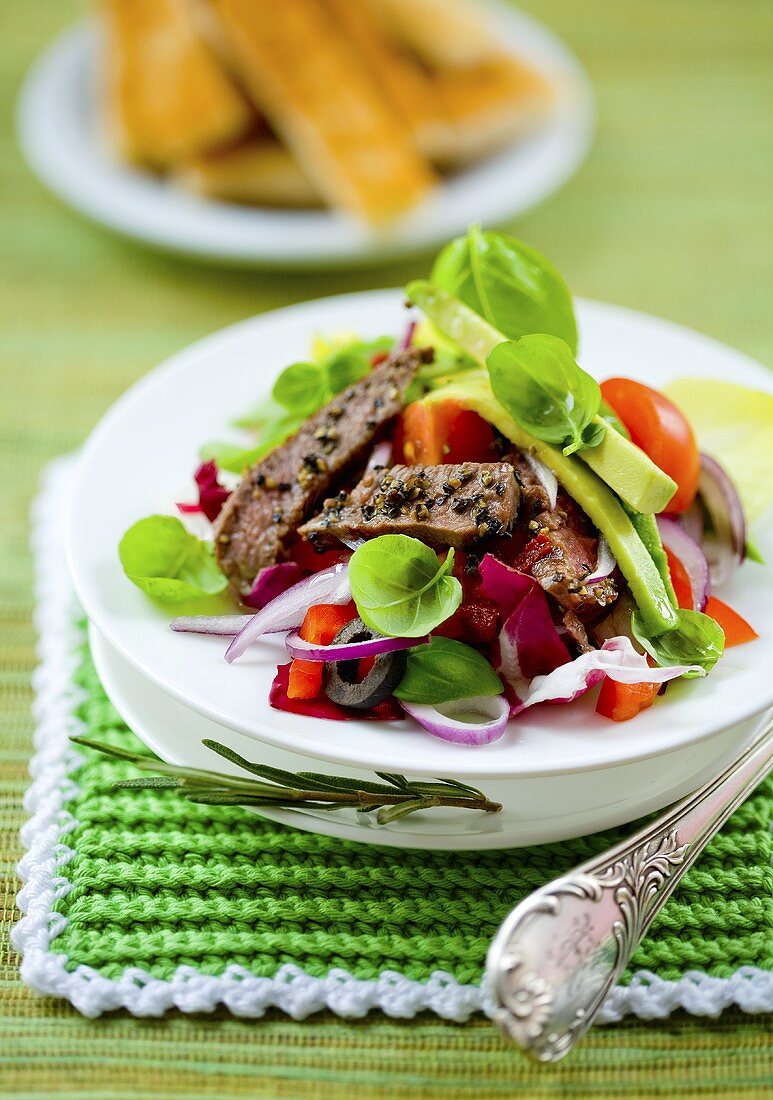 A colourful mixed salad with beef strips and avocado