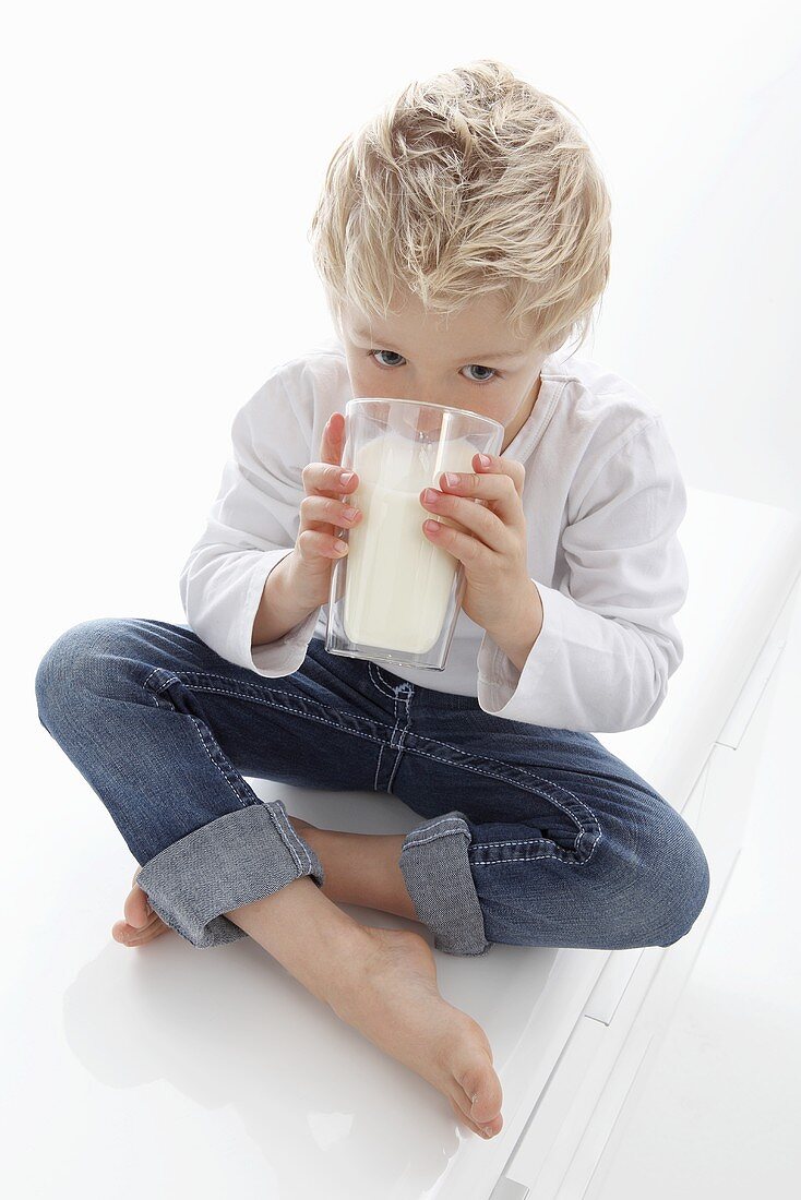 Kleiner Junge trinkt ein Glas Milch