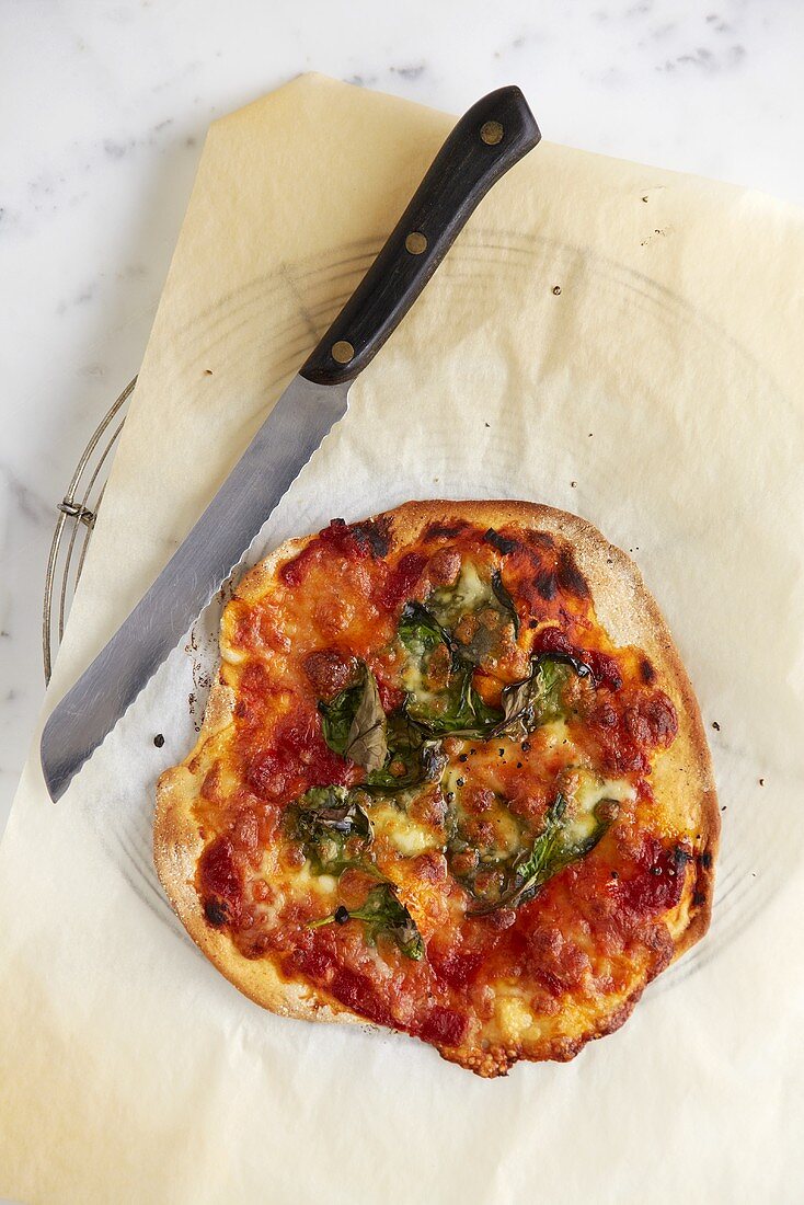 Pizza mit Tomaten, Mozzarella und Spinat auf Kuchengitter