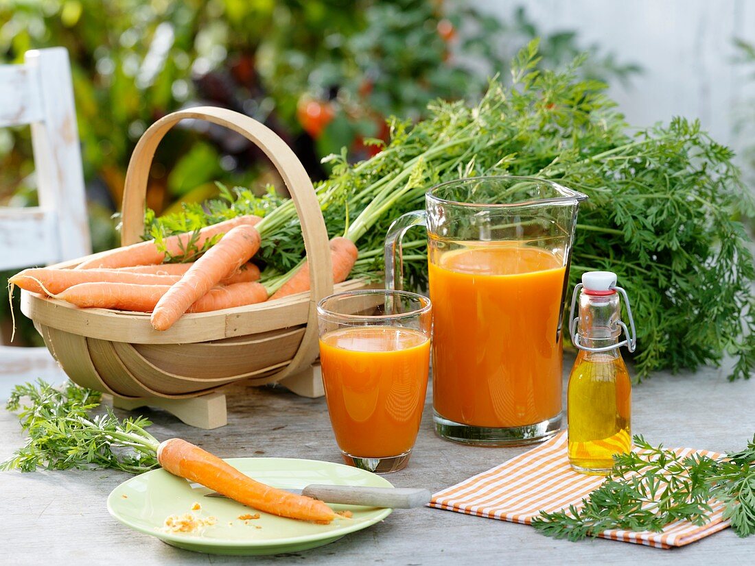 Carrot juice and fresh carrots on garden table