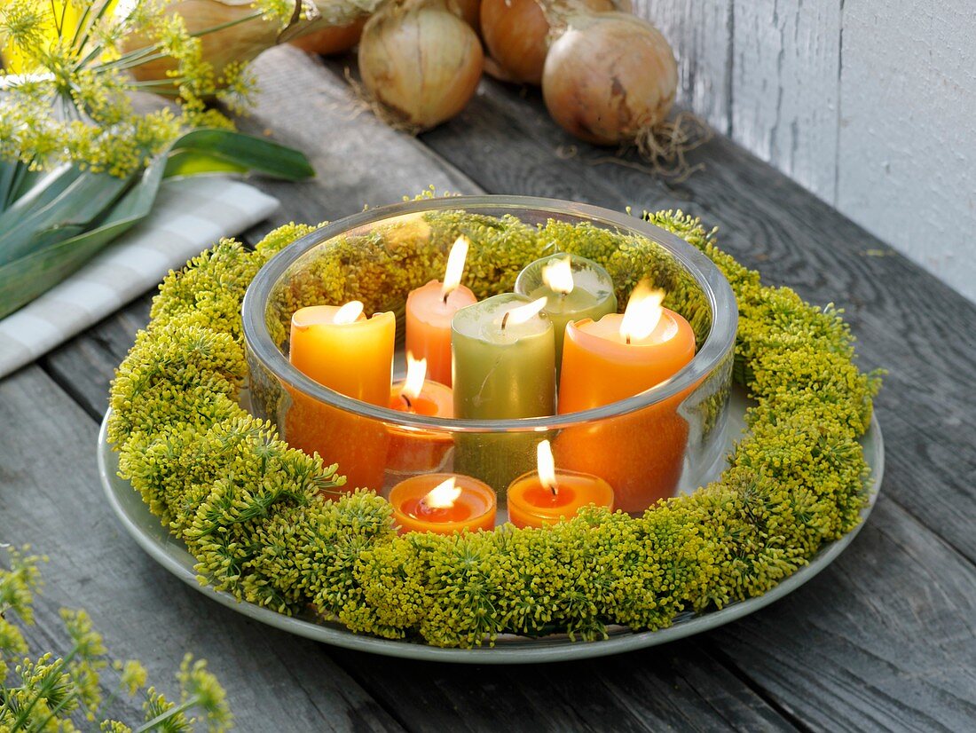 Wreath of fennel flowers around burning candles in glass