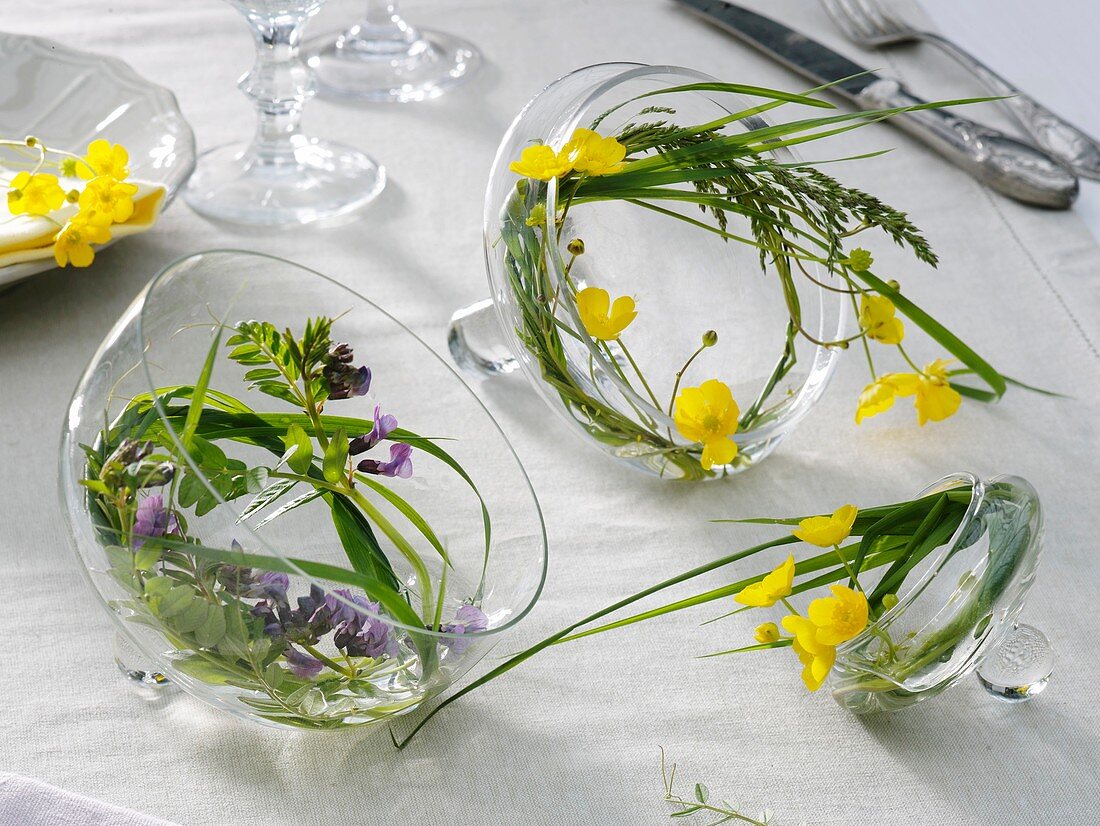 Kleine Kränze aus Gräsern und Blumen in Glasdeckeln