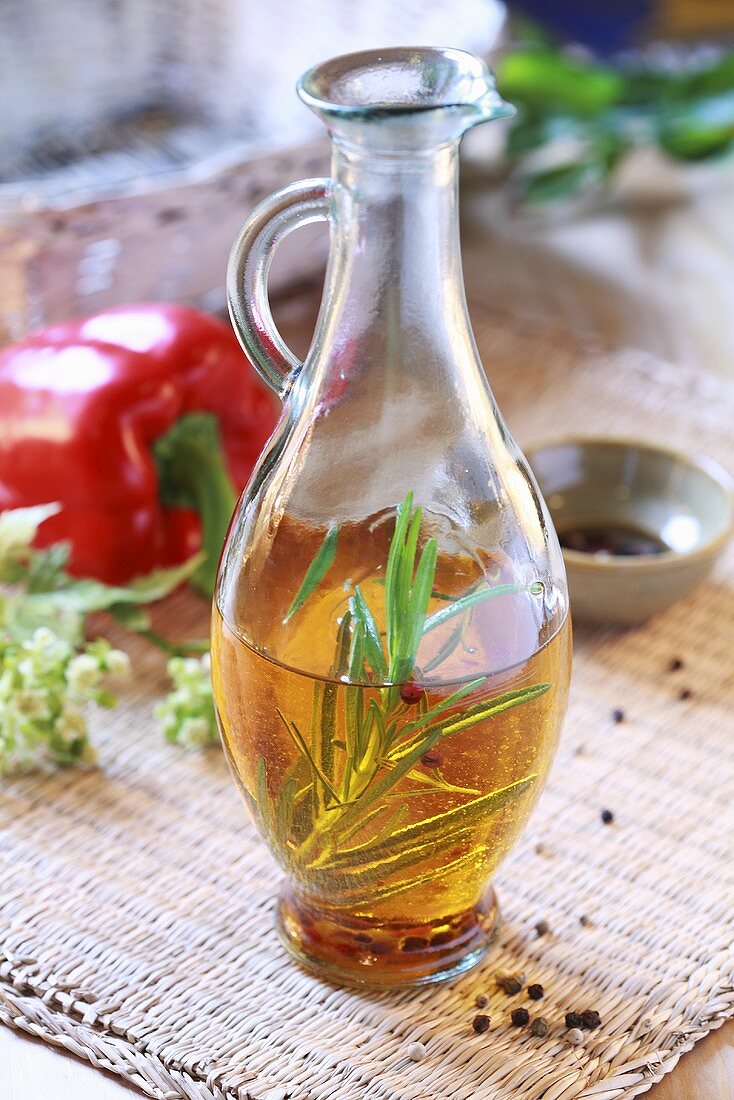 Olivenöl mit Kräutern, Paprika und Pfefferkörnern in Karaffe
