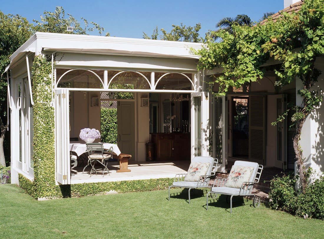 Conservatory extension in elegant, country-house style with arched transom windows above wide folding doors