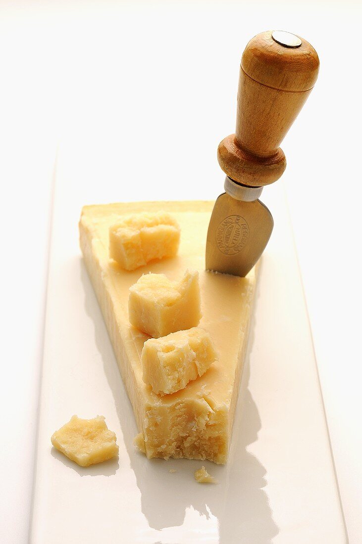 A piece of Parmesan cheese with cheese knife