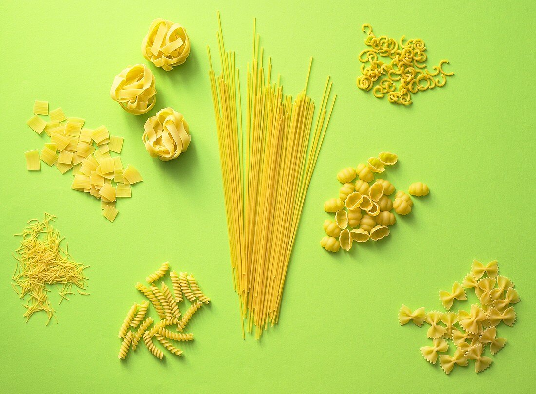 Various types of pasta on a green surface