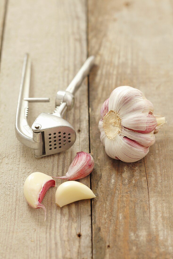 Garlic and a garlic press on a wooden surface