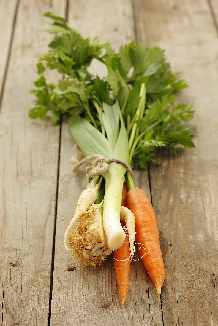 A bunch of soup vegetables on a wooden surface