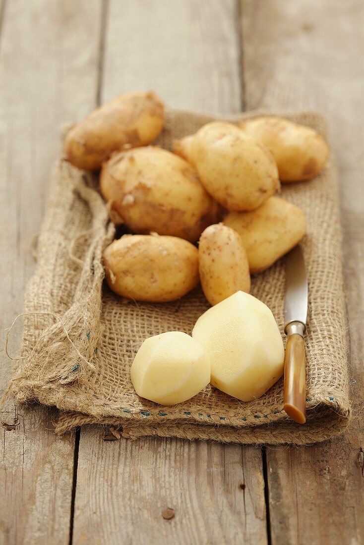 Neue Kartoffeln, teilweise geschält, auf Jutesack