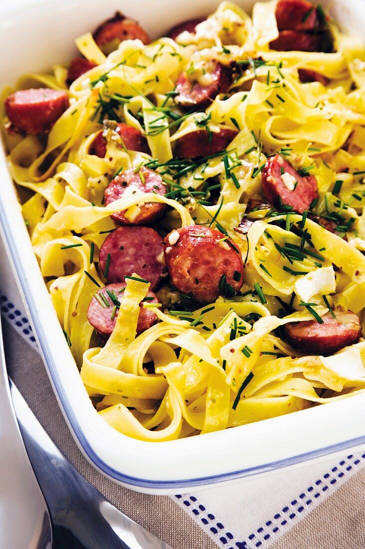 Baked tagliatelle with sliced sausages and Camembert