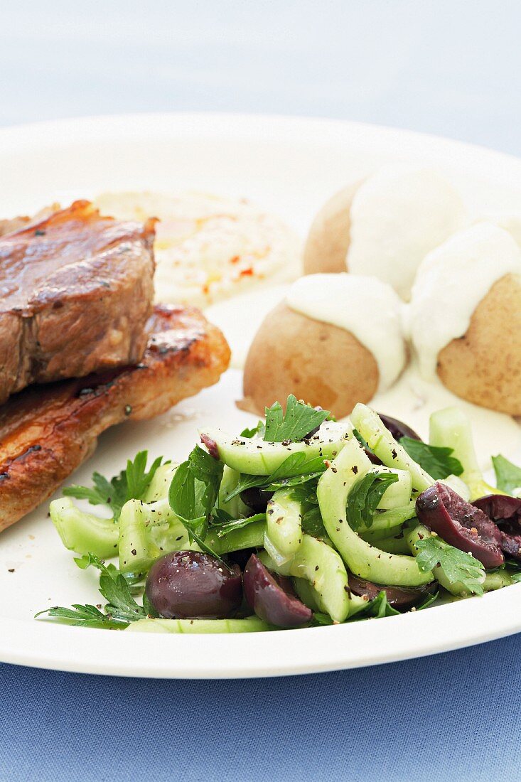 Grilled lamb steaks with Greek salad, potatoes and feta sauce