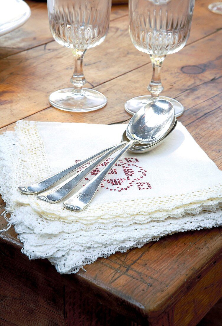 Servietten, Löffel und Weingläser auf einem Holztisch