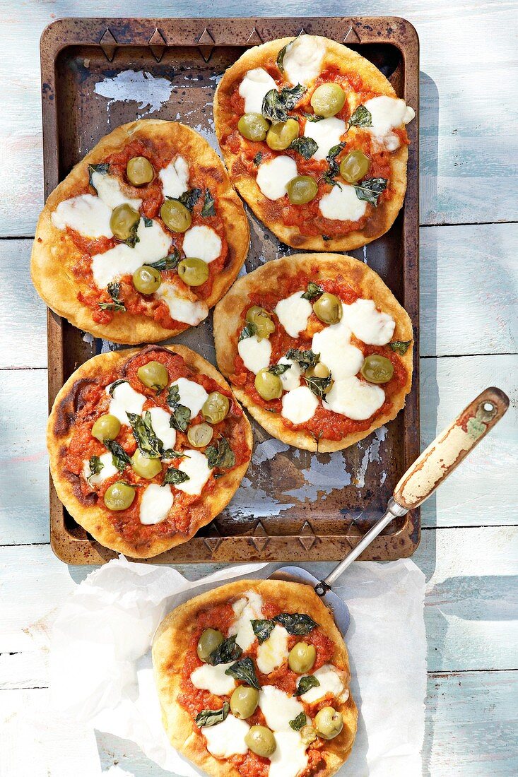 Mini-pizzas topped with olives and mozzarella