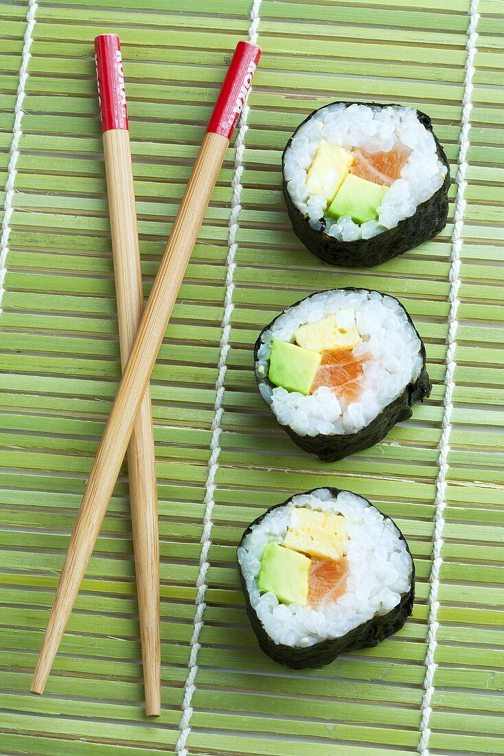 Maki sushi and chopsticks on bamboo mat