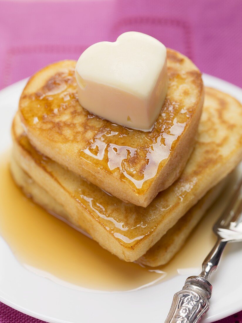Heart-shaped pancakes with maple syrup and butter