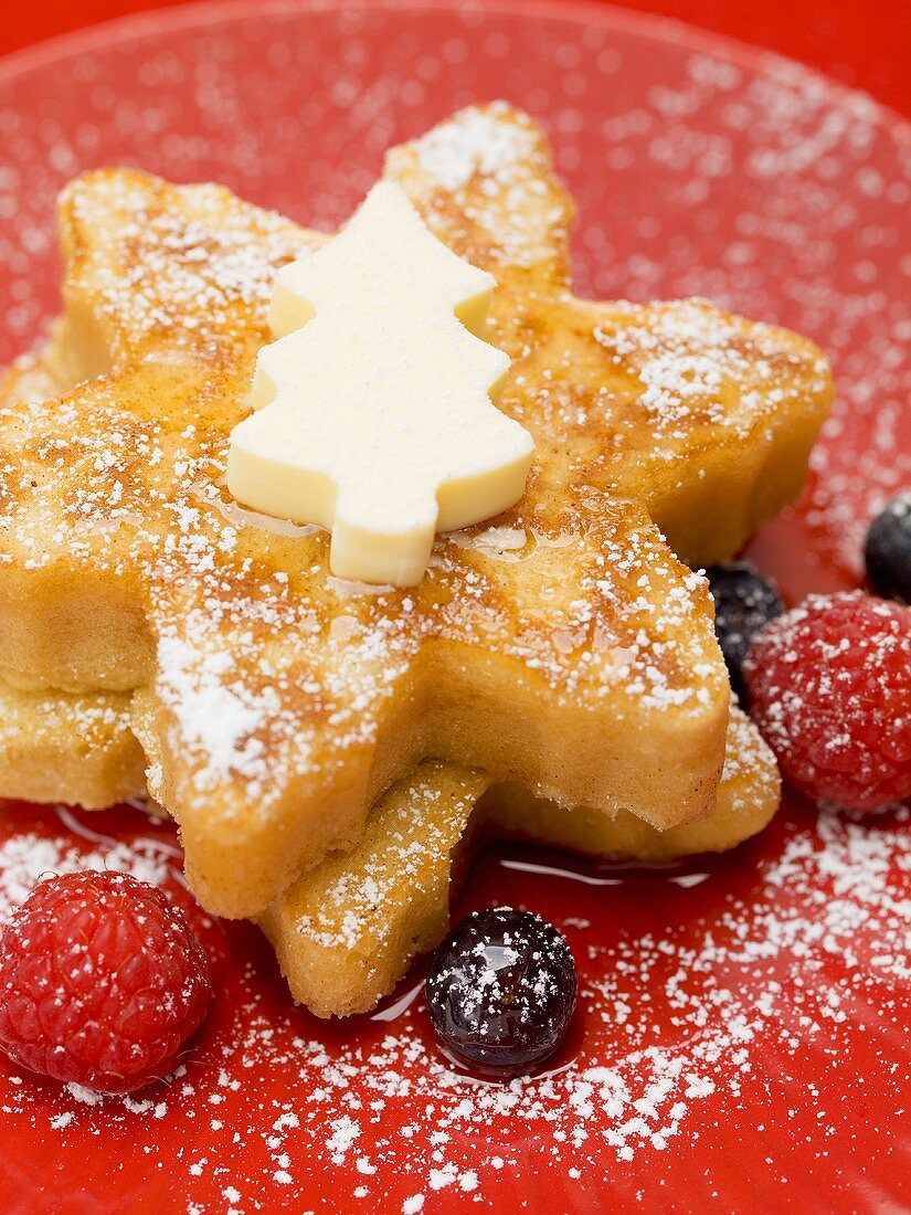 Star-shaped pancakes with butter, berries and maple syrup
