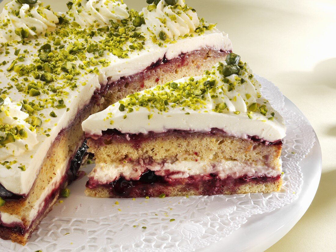 Quark cake with redcurrant jelly and pistachios, a piece cut