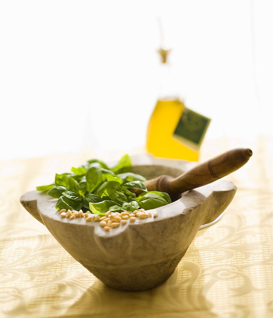 Fresh basil and pine nuts in a marble mortar with a pestle