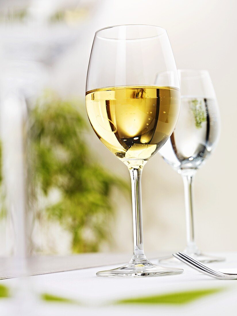 Glass of white wine and glass of water on laid table